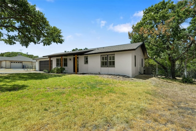 ranch-style house featuring central air condition unit, a front yard, and a garage