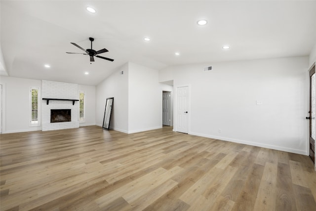 unfurnished living room featuring light hardwood / wood-style floors, vaulted ceiling, a brick fireplace, and ceiling fan