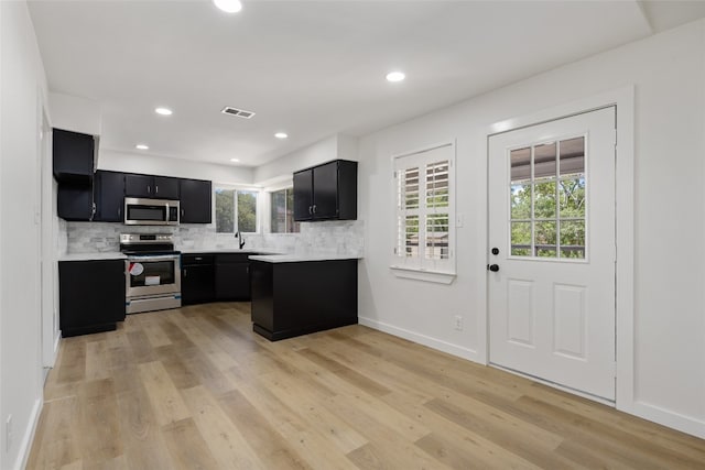 kitchen featuring stainless steel appliances, decorative backsplash, sink, and light wood-type flooring