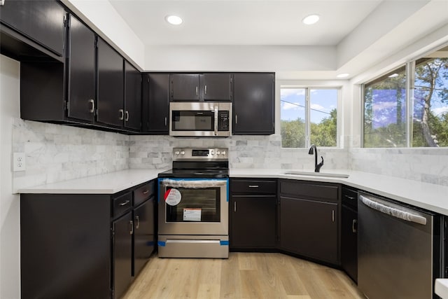 kitchen with light hardwood / wood-style flooring, appliances with stainless steel finishes, sink, and backsplash