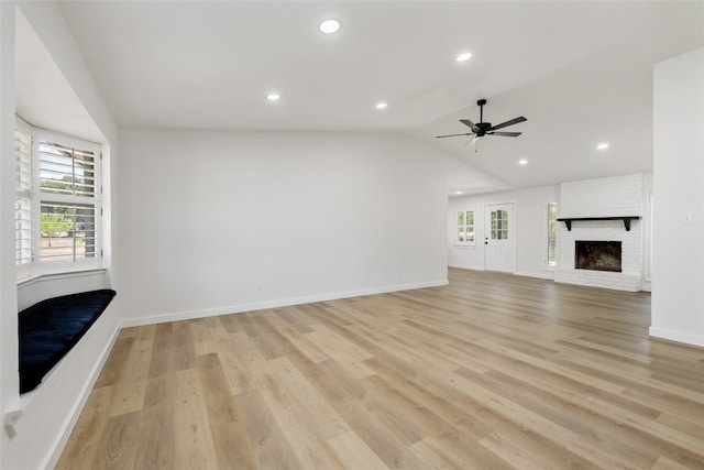 unfurnished living room with light hardwood / wood-style flooring, vaulted ceiling, a brick fireplace, and ceiling fan