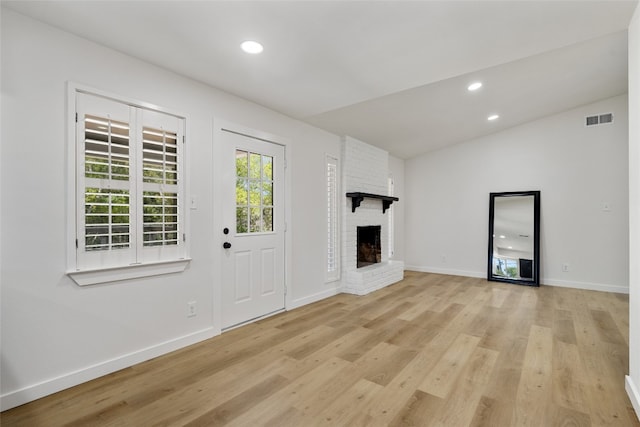 unfurnished living room with light hardwood / wood-style flooring, lofted ceiling, and a fireplace