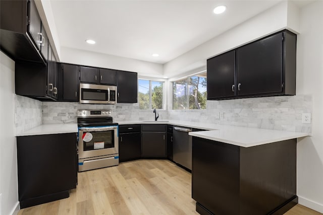 kitchen featuring decorative backsplash, sink, appliances with stainless steel finishes, and light hardwood / wood-style flooring