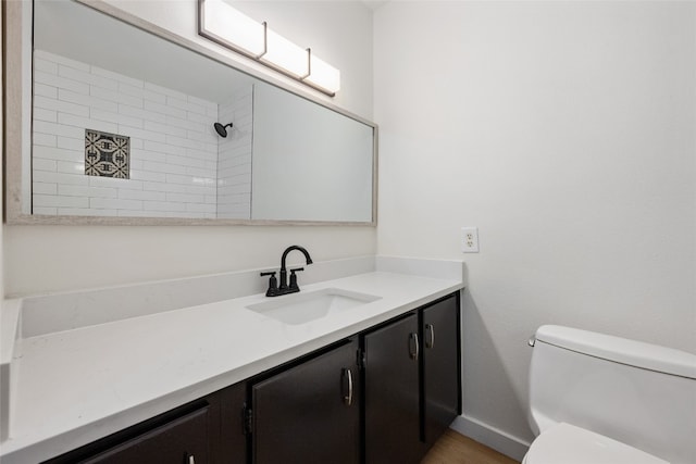 bathroom with toilet, vanity, and a tile shower