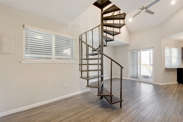 stairs with ceiling fan, high vaulted ceiling, and hardwood / wood-style floors