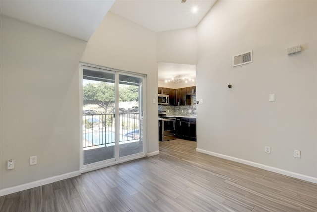 unfurnished living room with a towering ceiling and light wood-type flooring