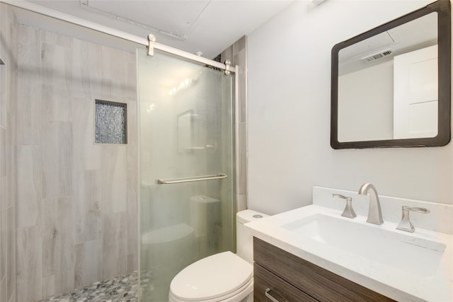 bathroom with vanity, toilet, and a shower with door