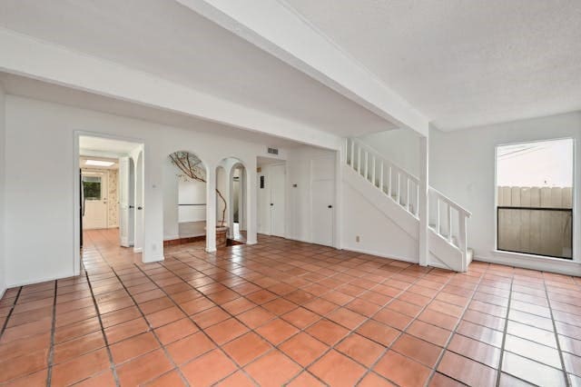 unfurnished living room with beamed ceiling and light tile patterned floors