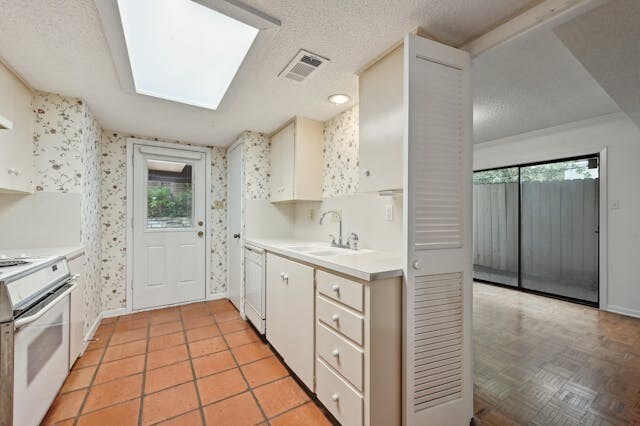 kitchen with a healthy amount of sunlight, sink, a skylight, and white appliances