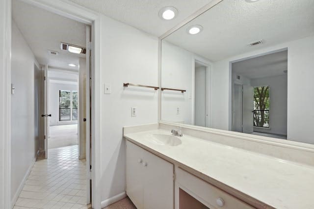 bathroom featuring vanity, a textured ceiling, tile patterned floors, and a wealth of natural light