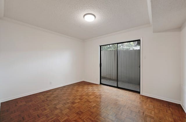 empty room with dark parquet floors, a textured ceiling, and ornamental molding