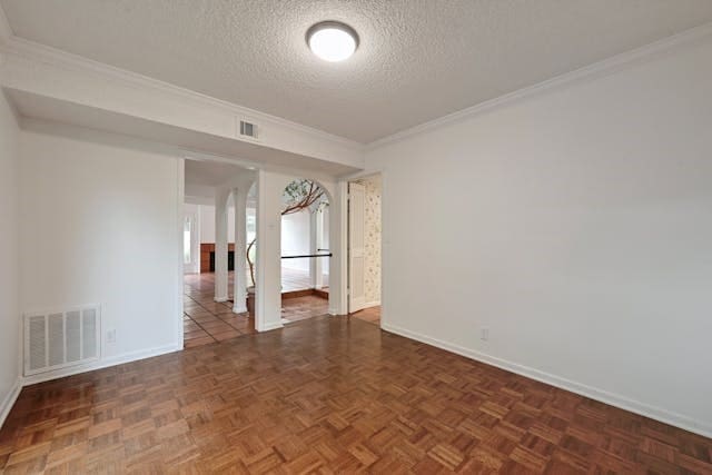 spare room featuring dark parquet floors, a textured ceiling, and ornamental molding