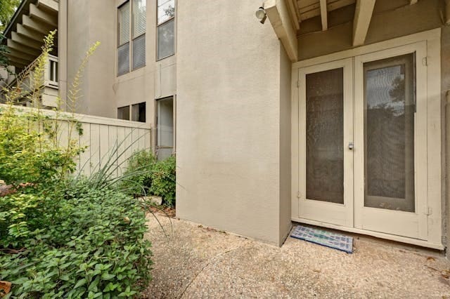 view of exterior entry with fence and stucco siding