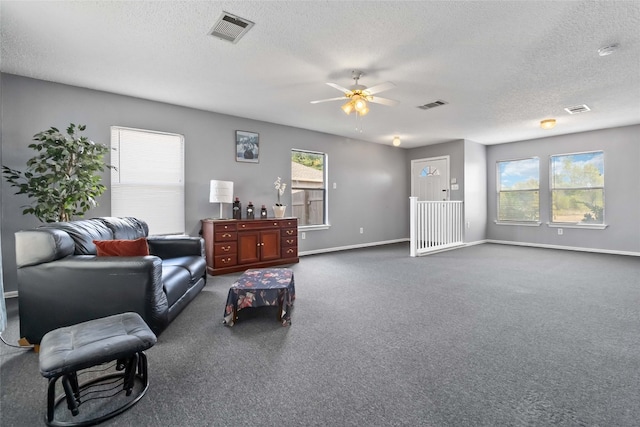 living room with ceiling fan, a textured ceiling, and dark carpet