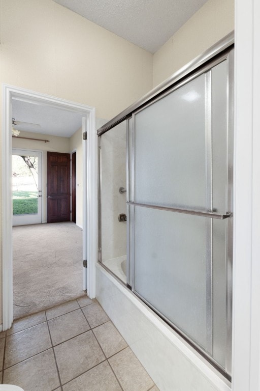 bathroom featuring a textured ceiling, shower / bath combination with glass door, and tile patterned flooring