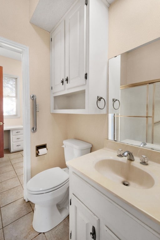 bathroom featuring toilet, walk in shower, vanity, and tile patterned flooring