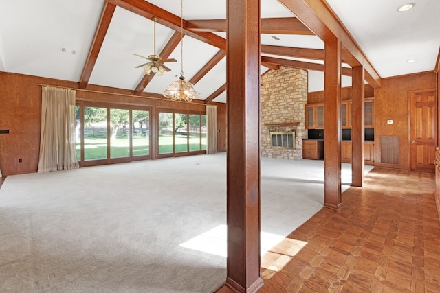 unfurnished living room featuring high vaulted ceiling, carpet flooring, beamed ceiling, a fireplace, and ceiling fan with notable chandelier