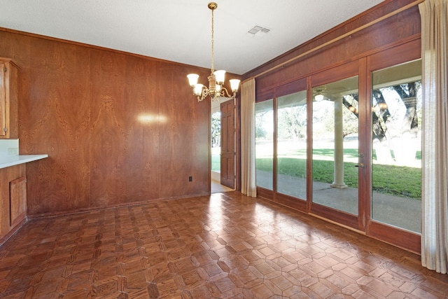 unfurnished dining area featuring a chandelier and wooden walls