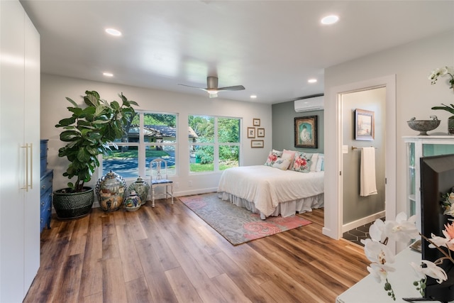 bedroom featuring ceiling fan, wood-type flooring, and a wall mounted AC