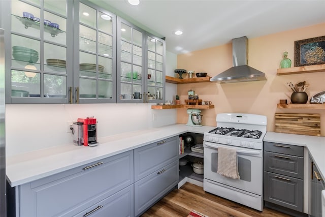 kitchen with wall chimney range hood, white range with gas cooktop, and dark hardwood / wood-style floors