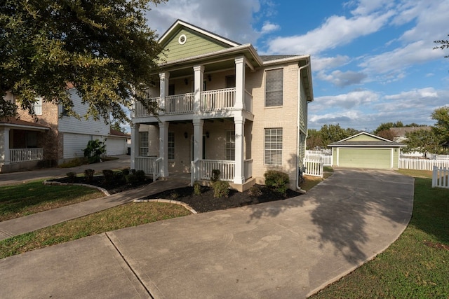 greek revival house with a porch, an outdoor structure, a balcony, a front lawn, and a garage