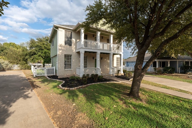 neoclassical home featuring a porch, a front lawn, and a balcony