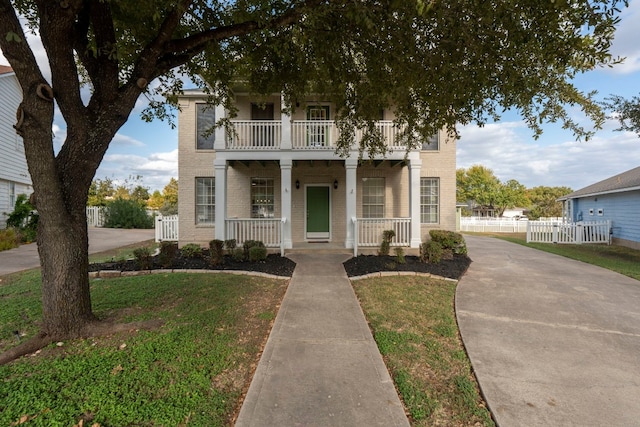 view of front of property featuring a front yard, covered porch, and a balcony