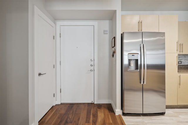 kitchen featuring decorative backsplash, stainless steel refrigerator with ice dispenser, hardwood / wood-style floors, and cream cabinetry