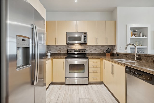 kitchen with backsplash, dark stone countertops, sink, light brown cabinetry, and appliances with stainless steel finishes