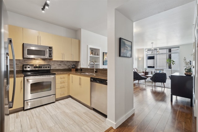 kitchen featuring sink, stainless steel appliances, decorative backsplash, light hardwood / wood-style flooring, and a chandelier