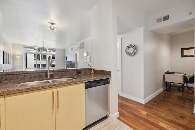 kitchen featuring sink, dishwasher, hardwood / wood-style flooring, dark stone countertops, and a notable chandelier