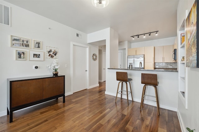 kitchen with dark wood-type flooring, backsplash, stainless steel appliances, and kitchen peninsula