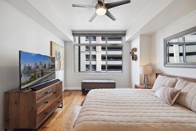 bedroom with ceiling fan, multiple windows, and light hardwood / wood-style flooring