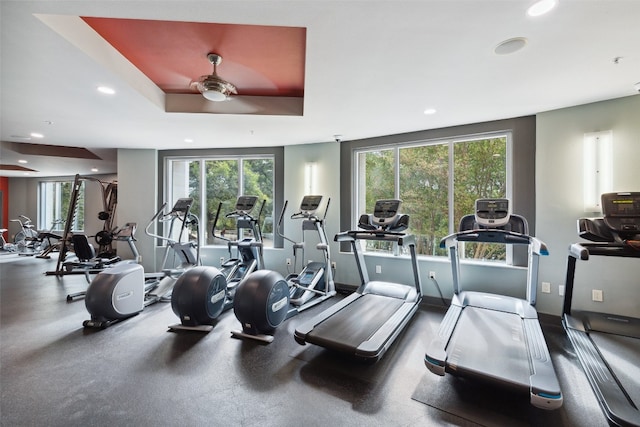 exercise room featuring ceiling fan and a tray ceiling