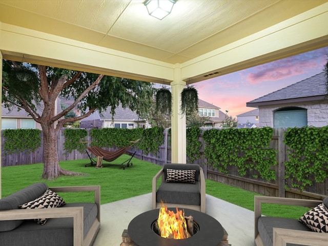 patio terrace at dusk featuring a fire pit and a yard