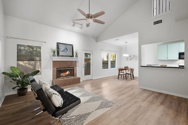 living area with visible vents, a high end fireplace, ceiling fan, wood finished floors, and baseboards