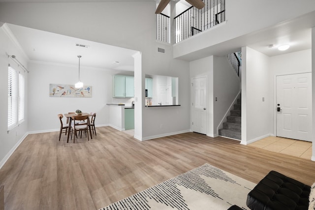 entrance foyer with light hardwood / wood-style flooring, crown molding, and a towering ceiling