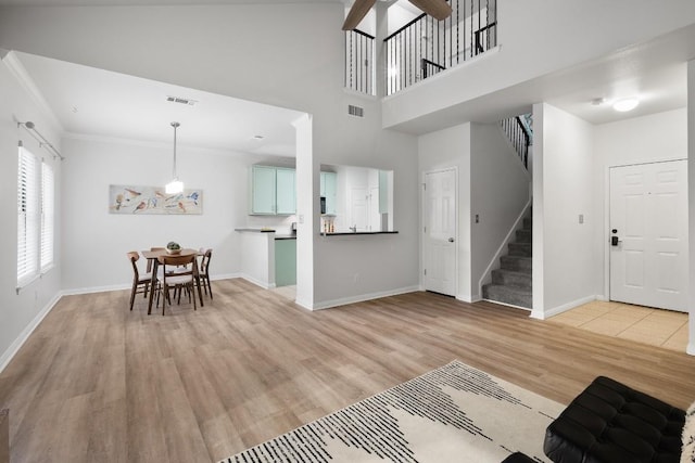 entrance foyer with crown molding, a high ceiling, and light wood-type flooring