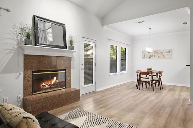 living room featuring a fireplace, visible vents, ornamental molding, wood finished floors, and baseboards