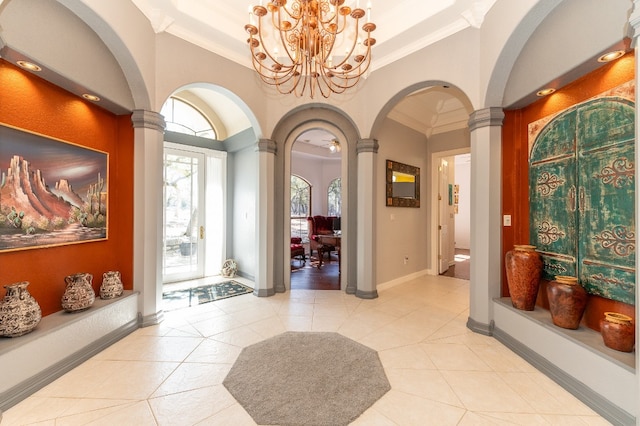 tiled foyer entrance with a notable chandelier, ornate columns, and crown molding