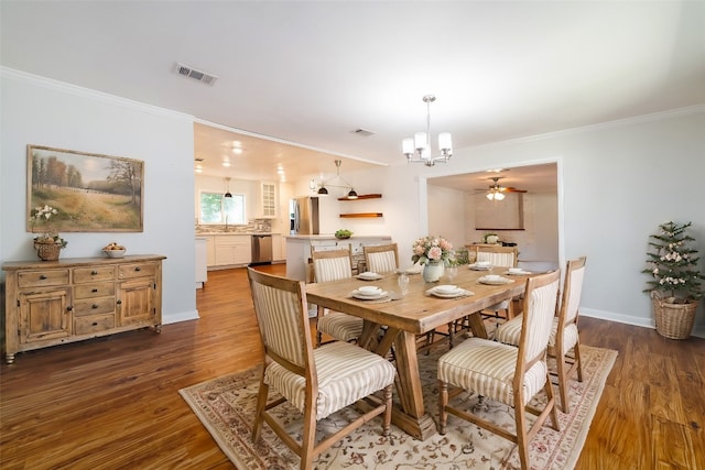 dining room with dark wood-type flooring, ornamental molding, and ceiling fan with notable chandelier