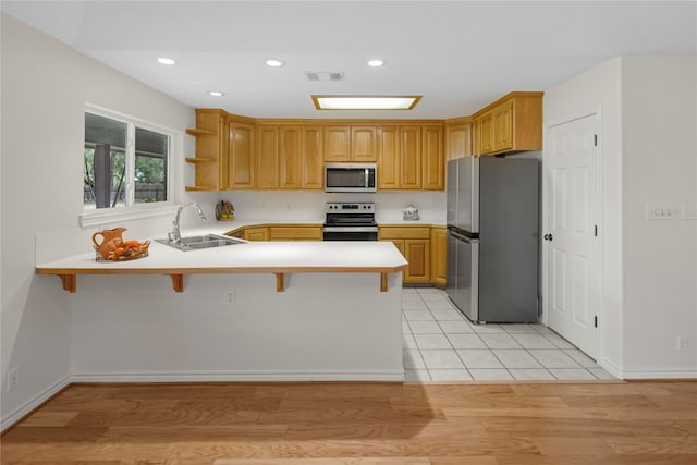 kitchen with a kitchen breakfast bar, kitchen peninsula, sink, and appliances with stainless steel finishes