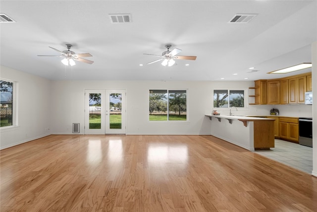 unfurnished living room featuring light hardwood / wood-style floors, ceiling fan, and sink