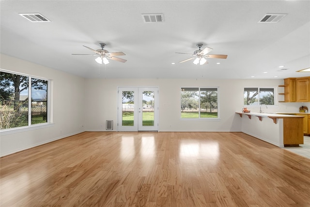 unfurnished living room with plenty of natural light, light hardwood / wood-style floors, and ceiling fan