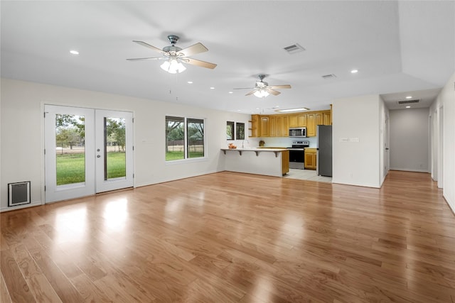 unfurnished living room with ceiling fan, french doors, a wealth of natural light, and light hardwood / wood-style flooring