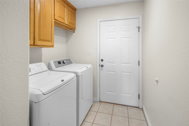 laundry room with washing machine and dryer, light tile patterned floors, and cabinets