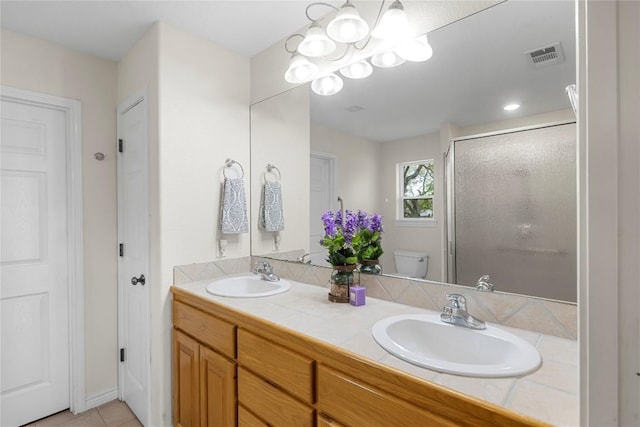 bathroom with vanity, a shower with door, an inviting chandelier, tile patterned flooring, and toilet