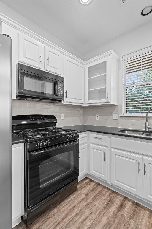 kitchen featuring white cabinets, backsplash, black appliances, light hardwood / wood-style floors, and sink