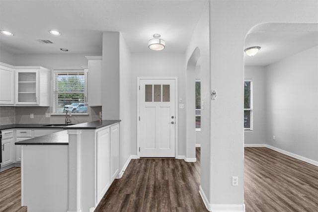 kitchen with kitchen peninsula, white cabinetry, sink, and dark wood-type flooring