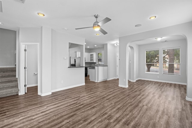 unfurnished living room featuring dark wood-type flooring and ceiling fan